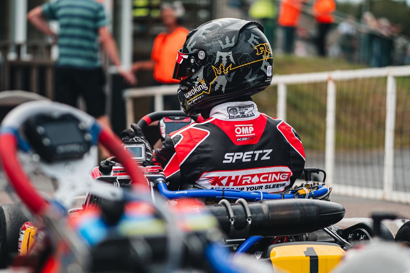 Driver in a KH Racing suit sitting in the kart, waiting for the start