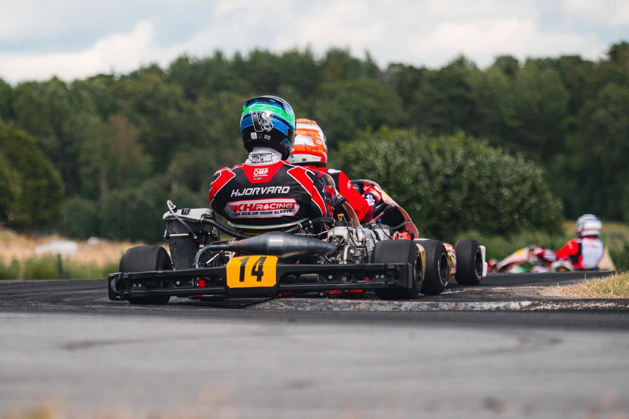 Kart number 14 from behind in a corner; the driver's suit reads HJORVARD and KH Racing