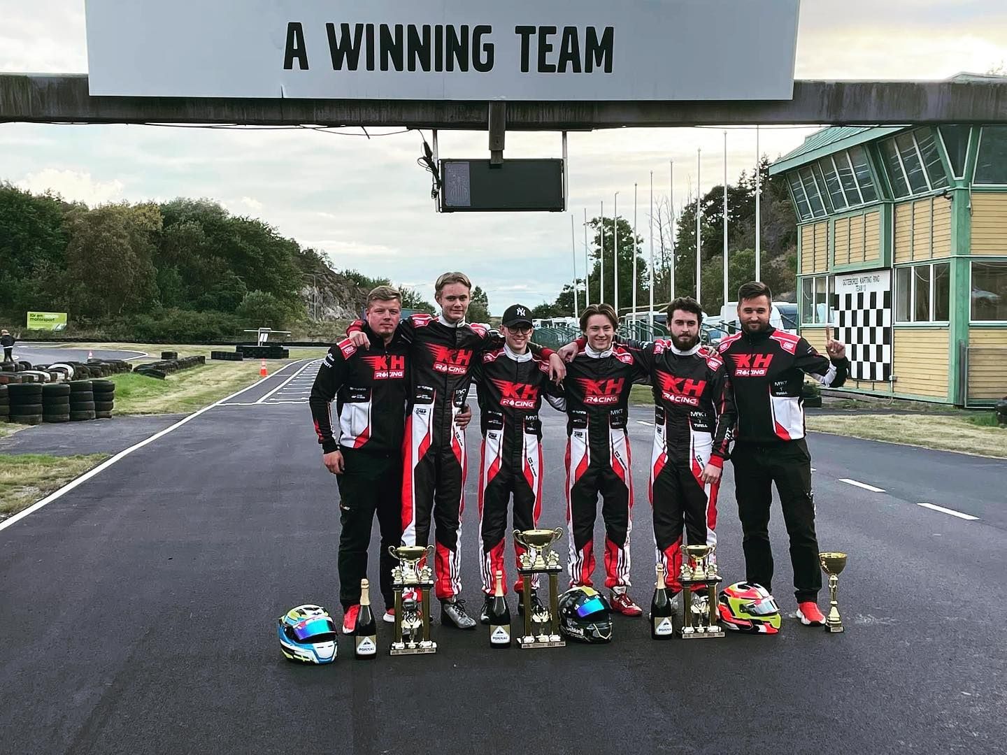 The team's drivers and mechanics under the "A winning team" sign